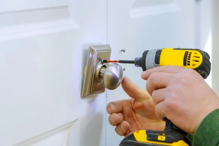 Låsesmed bruker en drill til å installere lås i døren