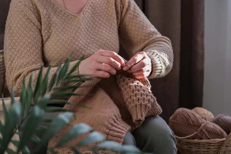 kvinne strikker ullgenser strikkepinner i nærheten tilbehør